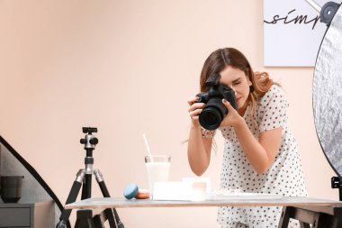 Genç bir kadın profesyonel stüdyoda badem kurabiyesi ve süt fotoğrafı çekiyor.