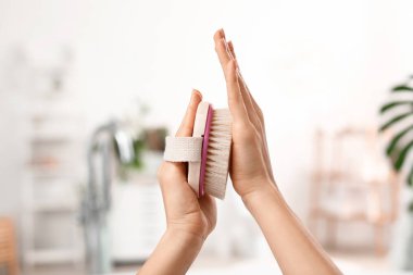 Banyoda masaj fırçası olan genç bir kadının elleri.