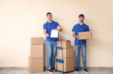 Renkli duvarın yanında kutuları olan teslimatçılar.