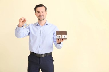 Evin anahtar ve modeline sahip erkek emlakçı.