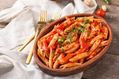 Ahşap masada lezzetli makarna ve domates soslu tabak.