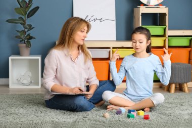 İçeride küçük bir kızla çalışan psikolog.