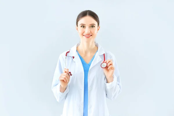 Retrato de médico feminino com estetoscópio em fundo claro — Fotografia de Stock