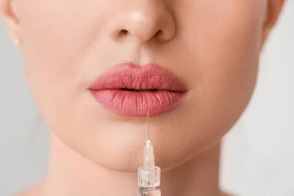 Young woman receiving filler injection against grey background, closeup — 스톡 사진