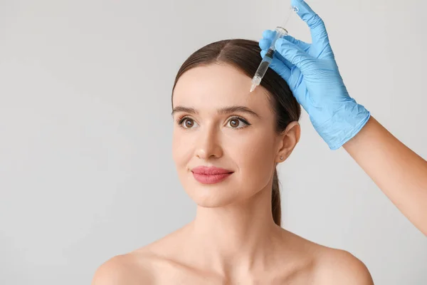 Young woman receiving filler injection against grey background — Stock Photo, Image
