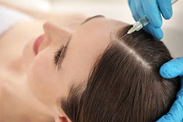 Молодая женщина с проблемой выпадения волос получает инъекцию в салоне красоты, крупным планом — стоковое фото