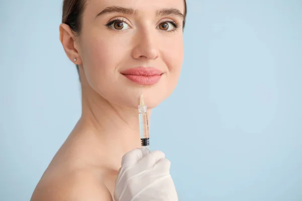 Jovem mulher recebendo injeção de enchimento contra fundo de cor — Fotografia de Stock
