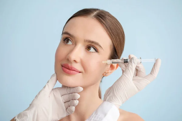 Young woman receiving filler injection against color background — Stock Photo, Image