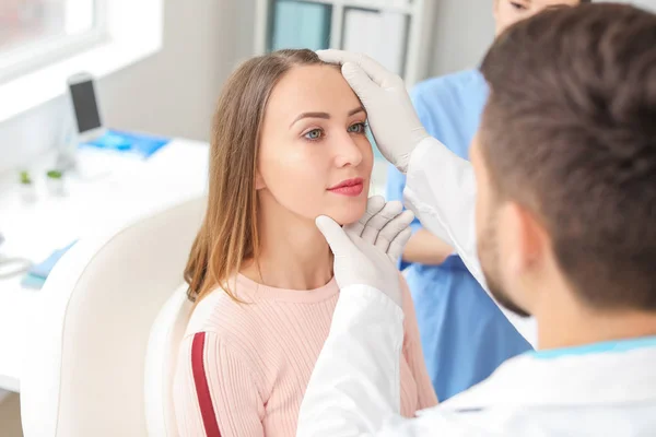 Cirujano plástico examinando la cara de la joven antes de la operación en la clínica — Foto de Stock