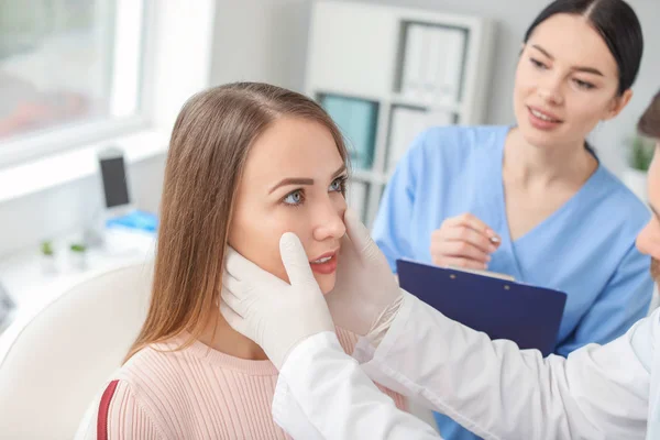 Plastic surgeon examining young woman's face prior to operation in clinic — Stock Photo, Image