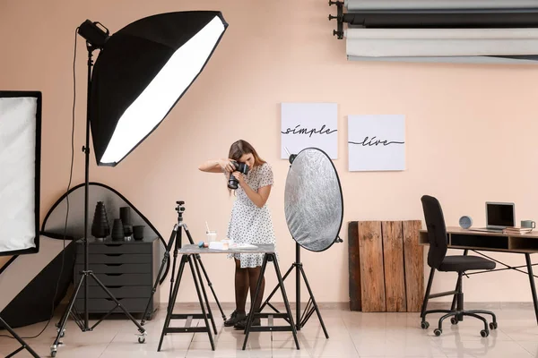 Young woman taking picture of macarons and milk in professional studio — Stock Photo, Image