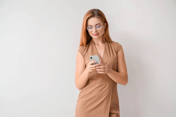 Retrato de hermosa mujer de negocios con teléfono móvil sobre fondo claro — Foto de Stock