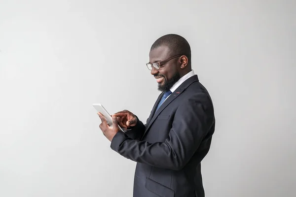 Portrait of African-American businessman with tablet computer on light background — Stock Photo, Image