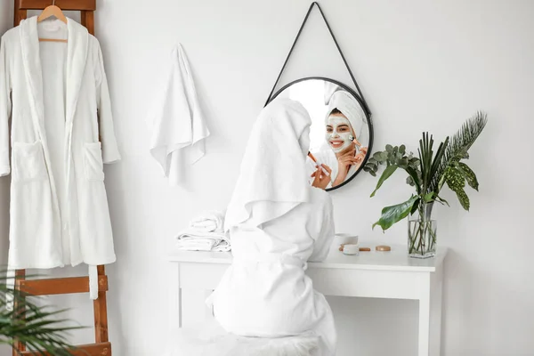 Красивая девушка надевает маску для лица в ванной комнате — стоковое фото