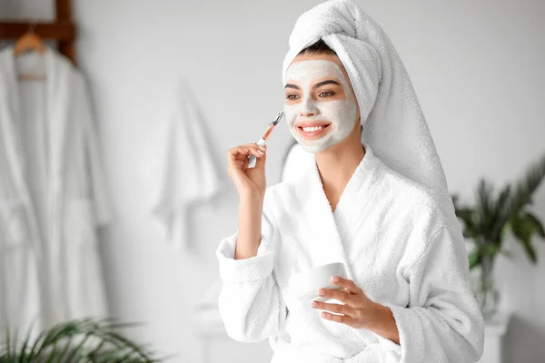 Mooie jonge vrouw toepassen van gezichtsmasker in de badkamer — Stockfoto