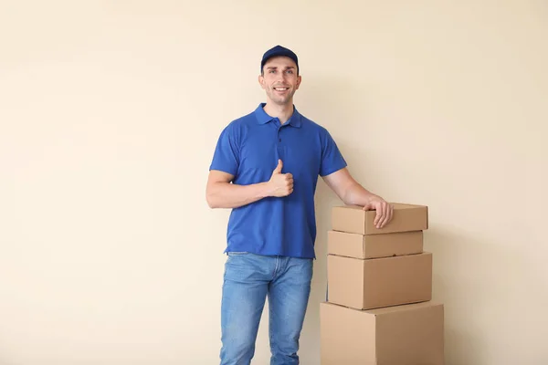 Entrega homem com caixas mostrando thumb-up em fundo de cor — Fotografia de Stock