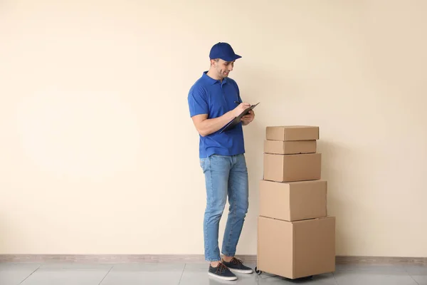 Delivery man with boxes near color wall