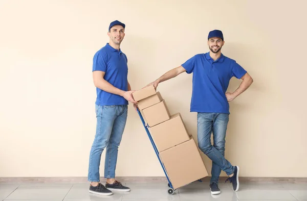 Entrega de homens com caixas perto da parede de cor — Fotografia de Stock