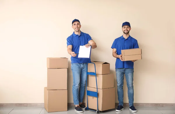 Delivery men with boxes near color wall