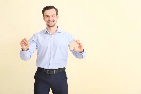 Male real estate agent with key on light background — Stock Photo, Image
