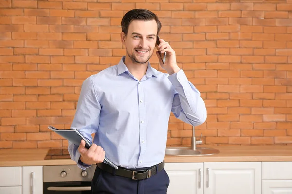 Porträt eines männlichen Immobilienmaklers, der mit dem Handy im Haus spricht — Stockfoto