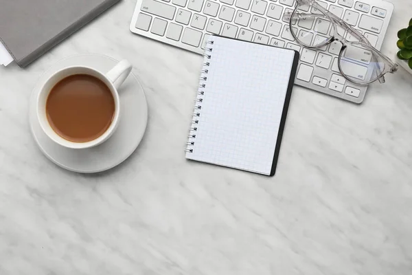 Notebook with cup of coffee and computer keyboard on table — Stock Photo, Image