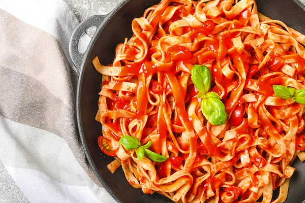 Padella con gustosa pasta e salsa di pomodoro in tavola, primo piano — Foto Stock