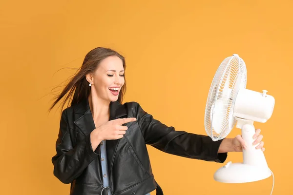 Young woman with electric fan on color background — Stock Photo, Image