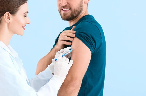 Doctor vaccinating young man on light background Stock Picture