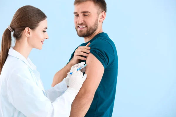 Doctor vaccinating young man on light background Royalty Free Stock Photos