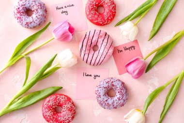 Renkli arkaplanda tatlı çörekler ve çiçeklerle kompozisyon