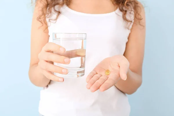 Young woman with fish oil and glass of water on color background, closeup — Stock Photo, Image