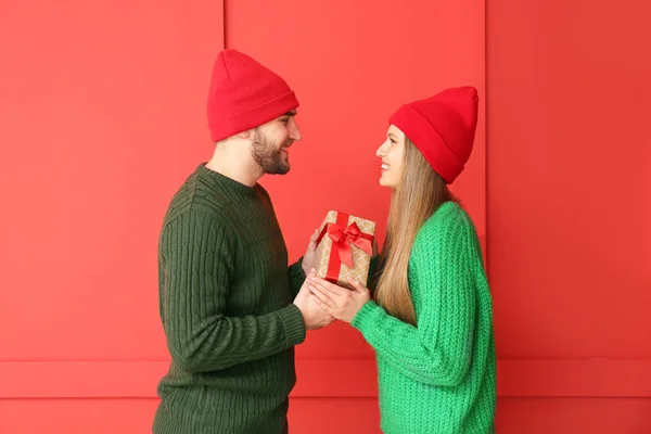 Щасливий чоловік дарує подарунок своїй дівчині на кольоровому фоні — стокове фото