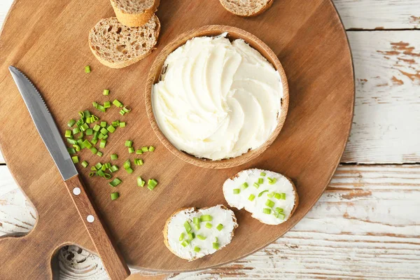 Свіжий хліб зі смачним вершковим сиром і зеленою цибулею на столі — стокове фото