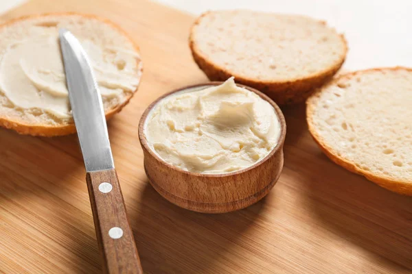 Pães frescos com queijo creme saboroso na tábua de madeira — Fotografia de Stock