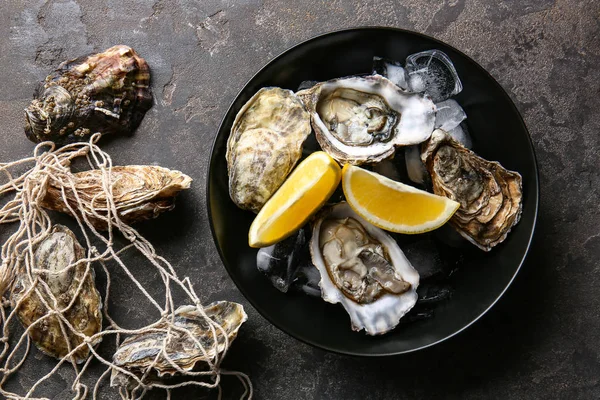 Plate with tasty oysters and lemon on grey background — Stock Photo, Image