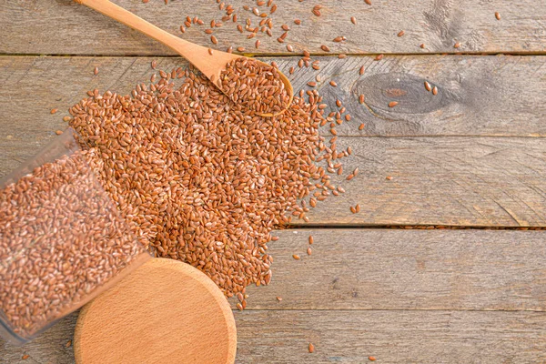 Overturned jar with flax seeds on wooden background — Stock Photo, Image