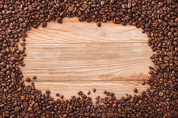 Frame made of coffee beans on wooden background