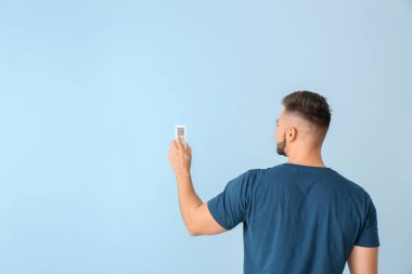 Renk arka plan üzerinde klima uzaktan kumanda ile genç adam