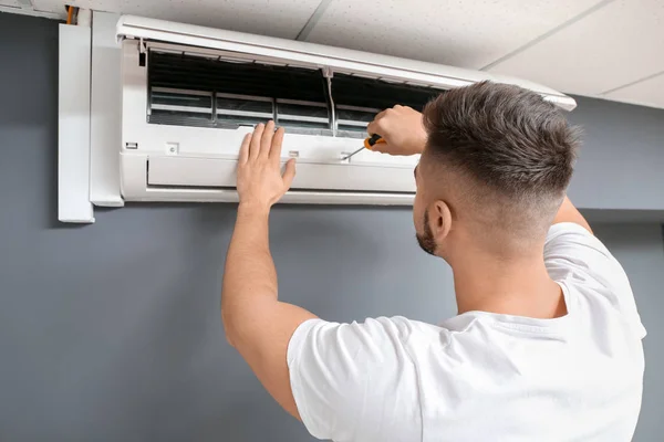 Técnico masculino reparando ar ar condicionado dentro de casa — Fotografia de Stock