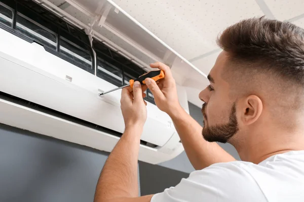 Técnico masculino reparando aire acondicionado en interiores —  Fotos de Stock