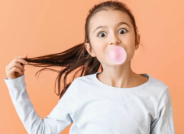 Niedliches kleines Mädchen mit Kaugummi auf farbigem Hintergrund — Stockfoto