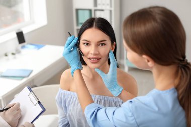 Klinikte hastanın yüzüne işaret uygulayan plastik cerrah