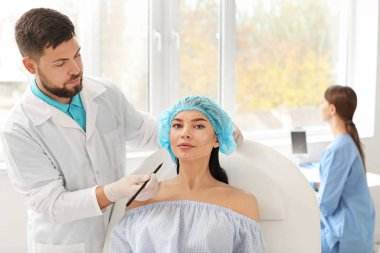 Klinikte hastanın yüzüne işaret uygulayan plastik cerrah