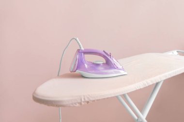 Işık arkaplanındaki elektrikli ütü ve tahta