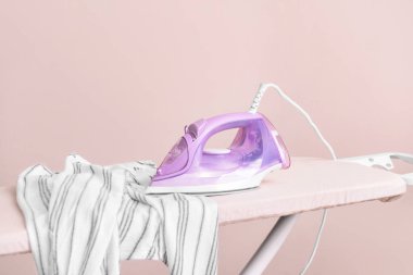 Işık arkaplanındaki elektrikli ütü ve tahta