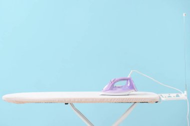 Renk arkaplanında elektrikli ütü ve tahta