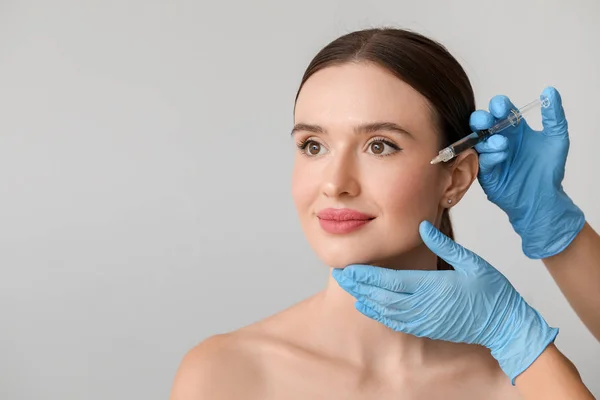 Young woman receiving filler injection against color background Stock ...