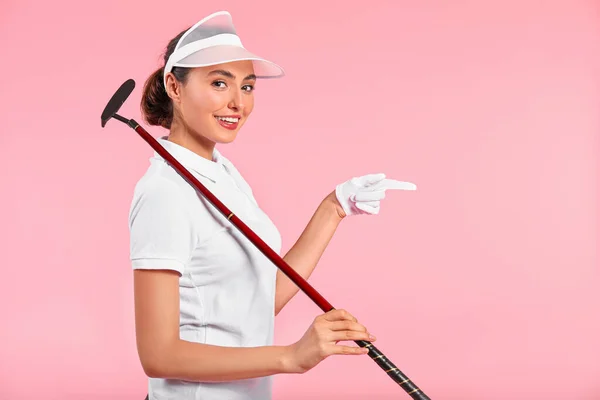 Mooie vrouwelijke golfer wijzend op iets op kleur achtergrond — Stockfoto