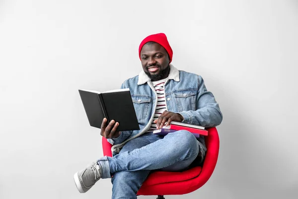 Hombre afroamericano leyendo libro sobre fondo claro — Foto de Stock